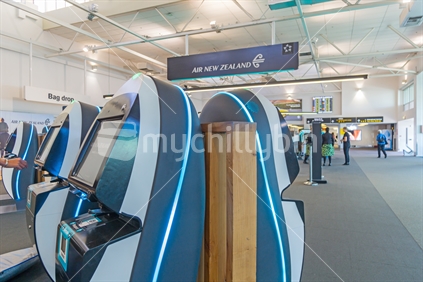 AUCKLAND, NEW ZEALAND - NOVEMBER 27, 2017; Bright Air New Zealand self-checkin terminals in Auckland domestic airport with people out of fiocus in background.