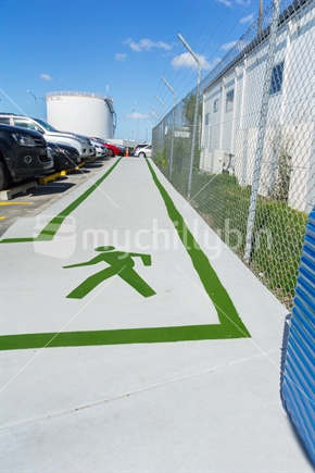 AUCKLAND, NEW ZEALAND - NOVEMBER 27, 2017; Green lines and green walking man sign on footpath showing way between international and domestic terminals with blue roller suitcase hinting at travel