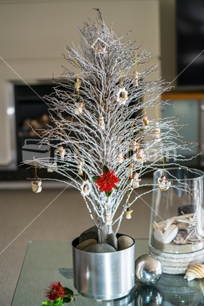 Simple summer New Zealand theme Christmas small white tree on glass table with seaside vase decoration and bright red pohutukawa flower in lounge.