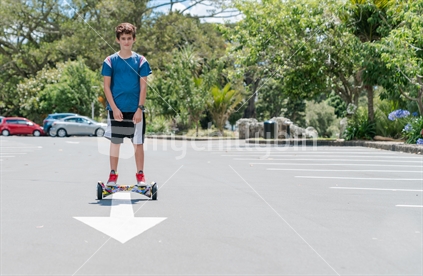 AUCKLAND, NEW ZEALAND - DECEMBER 27, 2017; Boy displays sense of balance riding hoverboard through carpark.