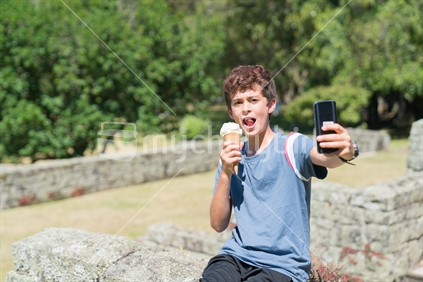 Boy taking selfie while enjoying ice cream outdoors on summer day