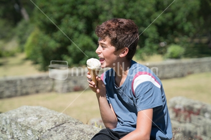 Boy licking ice cream outdoors on summer day