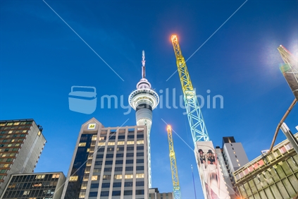 AUCKLAND, NEW ZEALAND - MARCH 25, 2018; Brightly illuminated Sky Tower and coloured antenna rising skyward from streets below.
