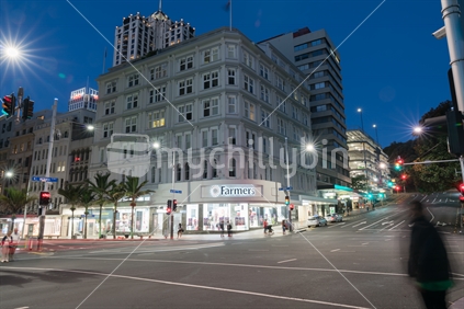 AUCKLAND, NEW ZEALAND - MARCH 25, 2018; Night scene corner Queen and Victoria Streets passing traffic and people in long exposure with department store Farmers illuminated across road (motion blur)