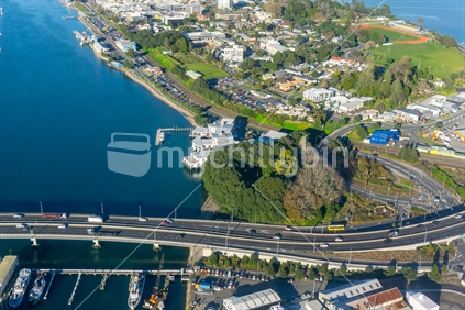 Aerial scene Tauranga city , harbour bridge and road flyovers below with boats in harbour.