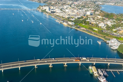 Aerial scene Tauranga city , harbour bridge and road flyovers below with boats in harbour.