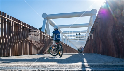 TAURANGA, NEW ZEALAND - AUGUST 12 2018; Cyclist crosses while pedestrians approach from other side of new white steel Takatimu Drive Overbridge is elevated pedestrial and cycle bridge crossing the highway below