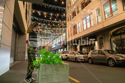 AUCKLAND, NEW ZEALAND - SEPTEMBER 14 2018; Auckland's Britomart area, bright and decorative lights, street furniture with young fashionable woman  at night, Raised ISO.