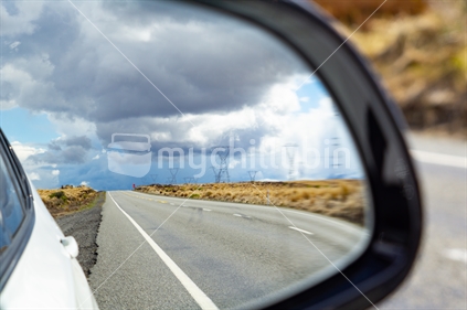 Driving State Highway 1 along Desert Road in   middle New Zealand North Island looking forward and in  vehicle mirror rear vision high country landscape and passing power pylons