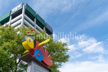 WELLINGTON, NEW ZEALAND - OCTOBER 1 2018; Yellow and red iconic New Zealand toy buzzy bee replicated in sculpture on top street sign for Bunny Street in front Victoria Building