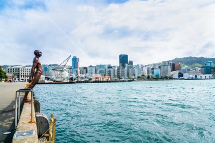 WELLINGTON, NEW ZEALAND - OCTOBER 1 2018; Wellington business district skyline forms background to public art statue known and Solice in  the Wind on the city waterfront.