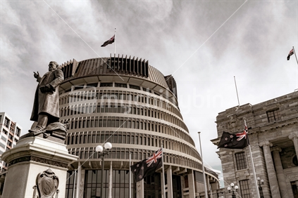 WELLINGTON, NEW ZEALAND - OCTOBER 1 2018; Capital city governmant buildings including circular conical shaped building known as Beehive with statue of Richard John Seddon a former famous politician pointing the way with right hand sepia toned.