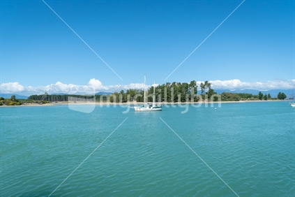 Waimea Estuary at Mapua on Tasman Bay with yacht moored center.