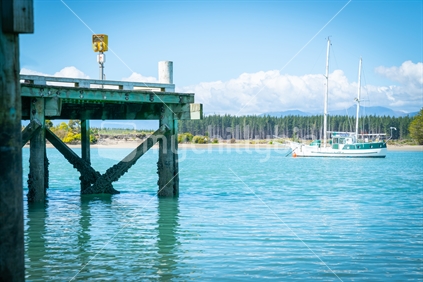 Wharf at Mapua with slopp moored in channel of Waimea Estuary on Tasman Bay in South Island New Zealand.