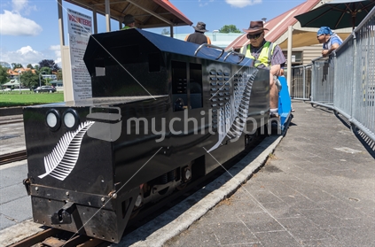 TAURANGA NEW ZEALAND - DECEMBER 16,2018; Model railway enthusiast engineers prepare vintage miniature train painted black with silver fern emblem giving rides.