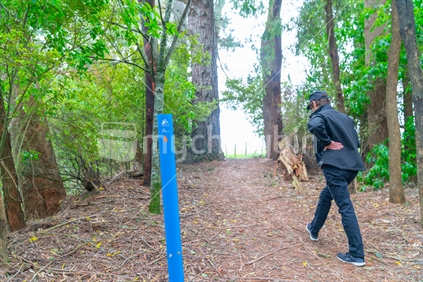 Arapuni, New Zealand - October 20 2019; Bright blue marker showing way on a New Zealand  Cycle Trail and Waikato River Trail along high bluffs above Waikato River through shady forest.