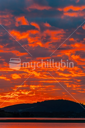 Fiery sky at dawn overlooking Tauranga Harbour to Papamoa hills.