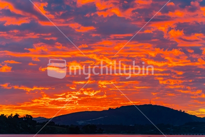 Fiery sky at dawn overlooking Tauranga Harbour to Papamoa hills.