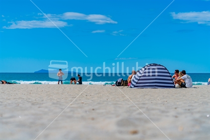 Tauranga New Zealand - January 16 2020; People enjoying summer day at Mount Maunganui Main Beach with sea view and Mayor Island on horizon.