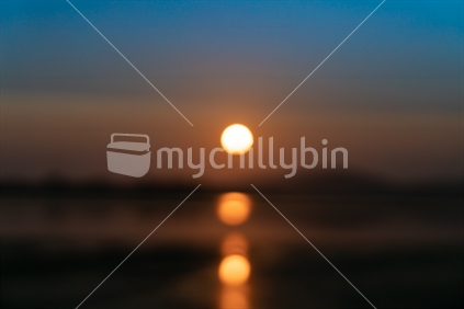 New Day, New Year golden sunrise over bay with defocused reflections and background