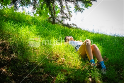 Teenage girl lying in green grass
