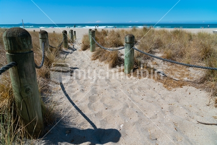 Beach access between rope and bollards across sand path at main beach Mount Maunganui, New Zealand.