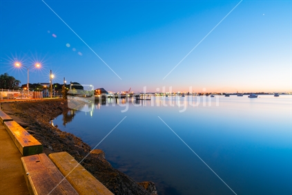Boats sway gently on Tauranga  Harbour with Bridge lights and reflections before sunrise with port cranes and Mount Maunganui landmark on distant horizon.