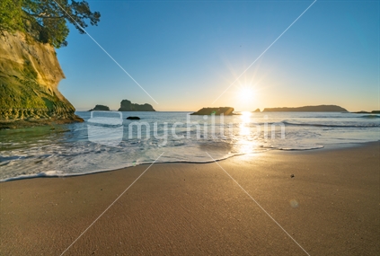 Golden water's edge, sunrise at Cathedral Cove  on Coromandel Peninsula New Zealand.