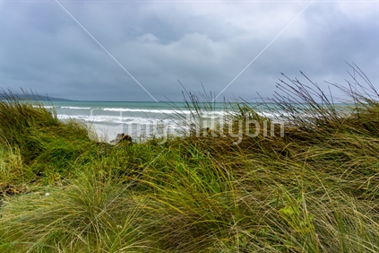 Windy overcast day with view out to horizon at Colac Bay in southern New Zealand coastal background.