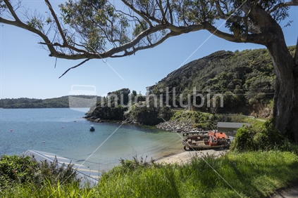 Leask Bay beach and boat sheds with beached old boat lying on sand on Sterwart Island, New Zealand.