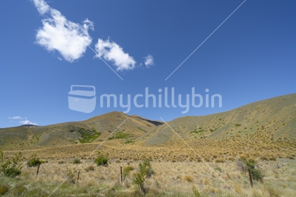 Peaks and tussock covered valleys of Lindis Pass, famous road trip Central Otago New Zealand.