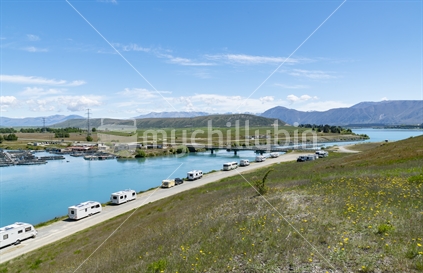 Twizel New Zealand - November 11 2020; Famous turquoise trout and salmon fishing destination Ohau Canal with trailer and mobile homes parked along siide at Twizel