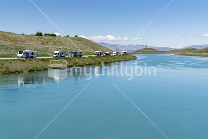 Twizel New Zealand - November 11 2020; Famous turquoise trout and salmon fishing destination Ohau Canal with trailer and mobile homes parked along siide and reflected in water at Twizel