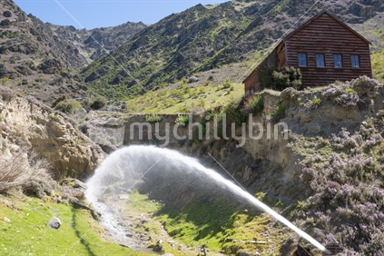 Cromwell New Zealand - November 10 2020; Water jet for sluicing under old hut on side of hill at site of old historic gold mining village in Kawarau Gorge