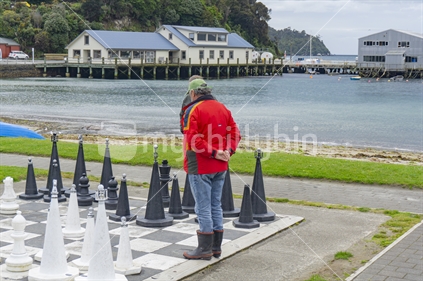 Oban, New Zealand - October 31 2020; Chess players on oversized outdoor board and set on Half Moon Bay waterfront, Stewart Island.