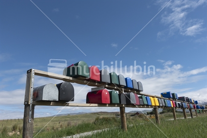 Rows of multi-coloured rural letterboxes on country road.