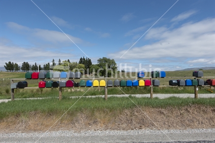 Rows of multi-coloured rural letterboxes on country road.