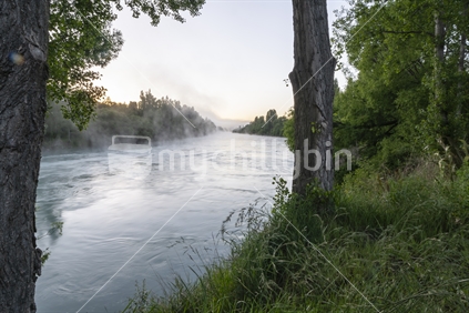 Early morning mist rises from Clutha River Cromwell in Central Otago New Zealand.