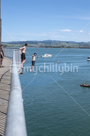Tauranga New Zealand - December 6 2020; Jumping from historic steel truss Tauranga Railway bridge in harbour below.