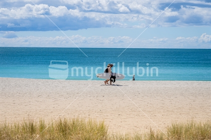 Tauranga New Zealand - March 22 2023: Mount Maunganui Main Beach background scene with people walking carrying surfboard.