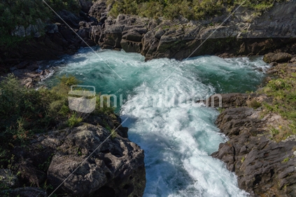 Water surges between rocky ledges into turquoise green pool at Aratiatia, Taupo.