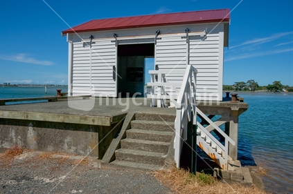 Historic wharf shed with view across bay at Big Omaha, New Zealand.