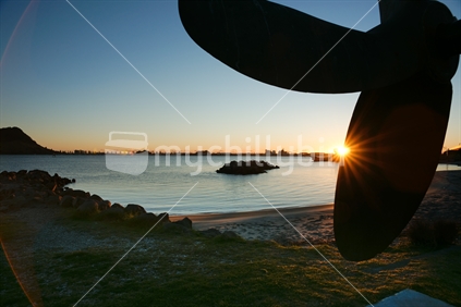 Sunrise over Mount Maunganui and Tauranga, as sun bursts over the harbour silhouetting the Mount and the propeller of the old tug, Taioma. New Zealand