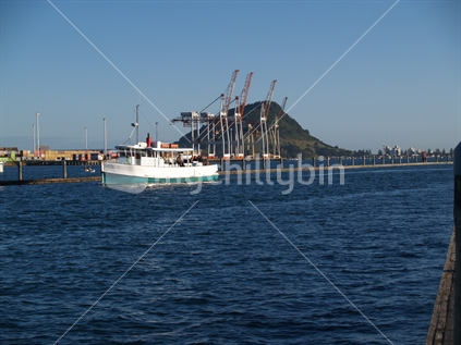 Mount maunganui with port container cranes and boat leaving marina in foreground