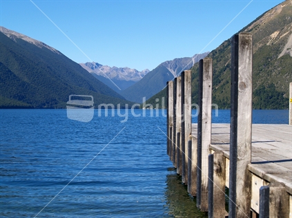 View across lake to converging distant hills and foreground Jetty on Lake Roto-iti, South Island