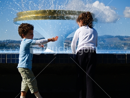 Two children playing by Tauranga Memorial Park fountain.