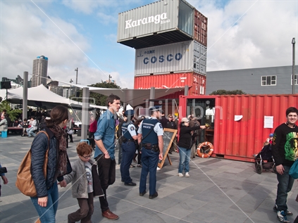 Karanga Plaza, on opening day of the Wynyard Quarter, Auckland waterfront, New Zealand. Showing the information centre constructed from shipping containers, 2011. Also shows police on duty mingling with the crowd.