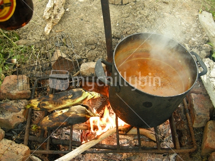 Cooking Dahl and corn on the cob over an open fire while camping