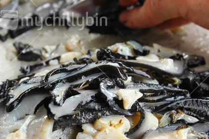 Closeup of paua being sliced in preparation for cooking.