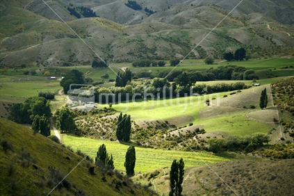 A break in the clouds spotlighting a beautiful green valley in Central Otago.
